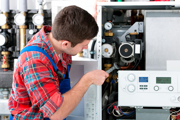 HVAC technician inspecting and repairing boiler controls in Buckeye