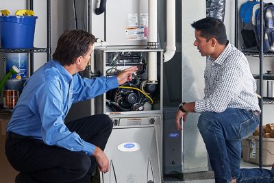 65df8c11f3e4c468cbd351a5_furnace repair vs replacement – Copy HVAC technician explaining furnace repair and maintenance to a homeowner in Buckeye, AZ